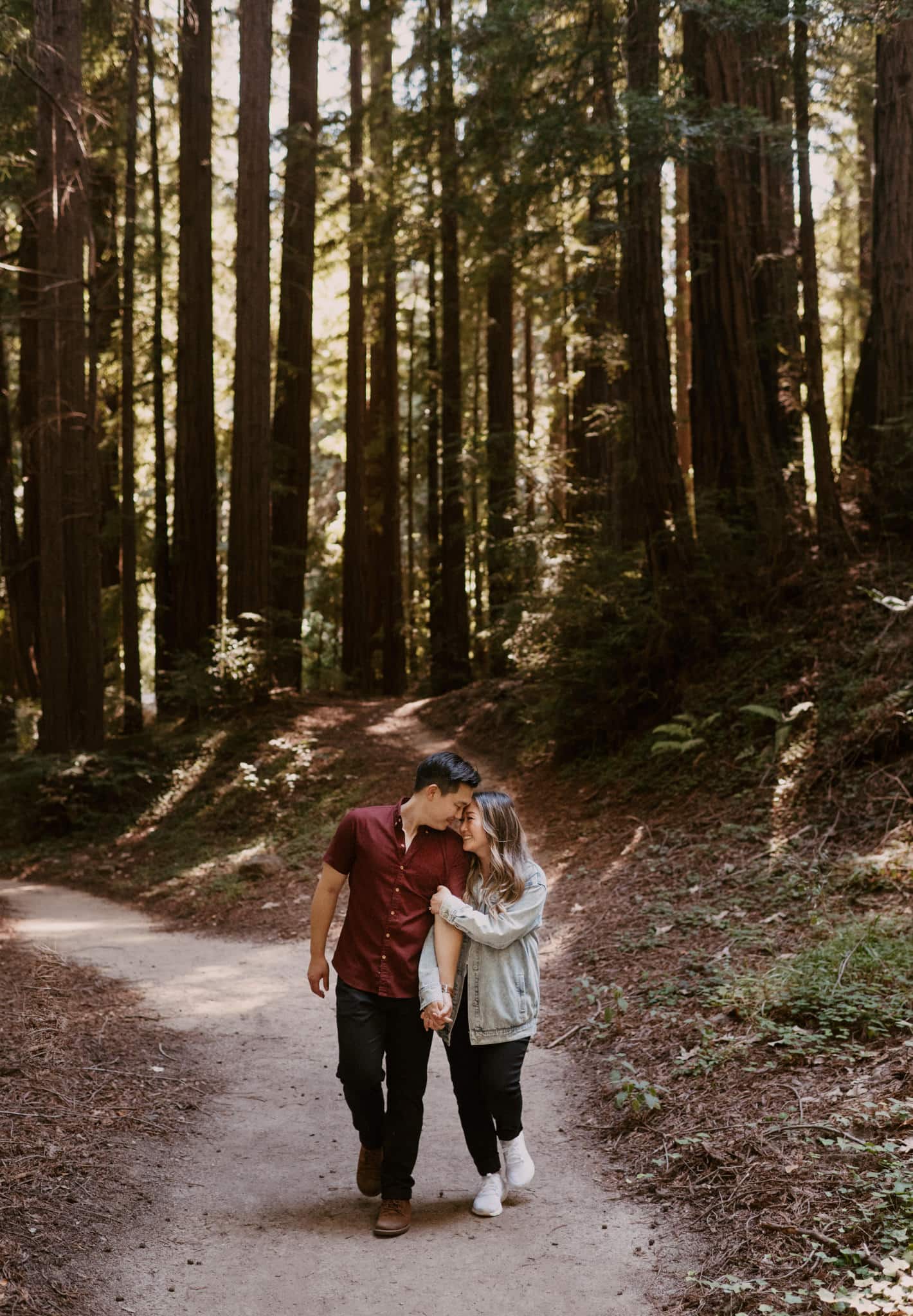 couple walking through the redwoods holding hands